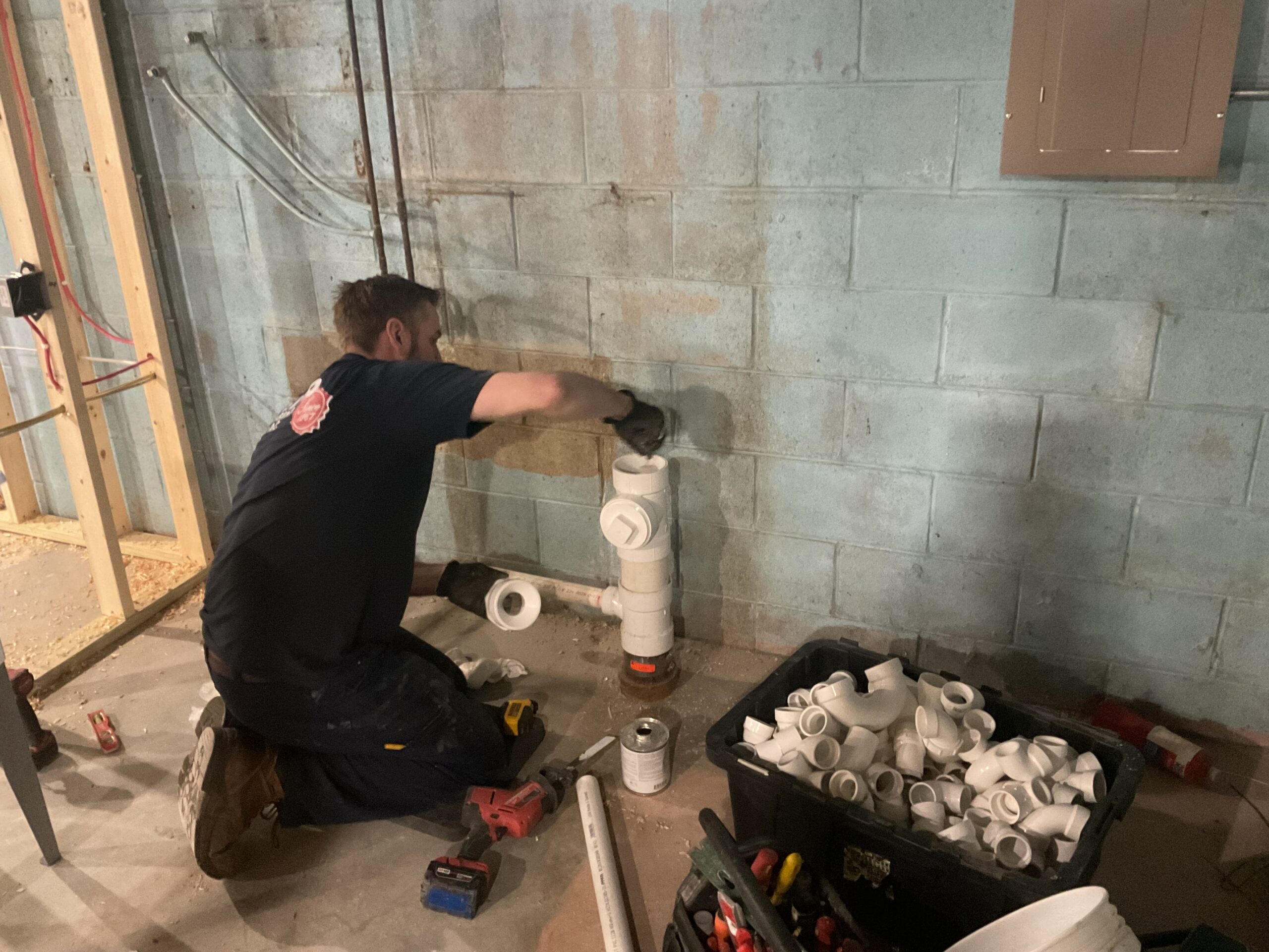 Albiero tech assembling drain fittings in basement
